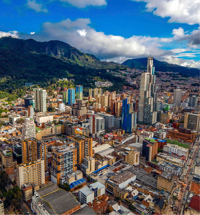 aerial view of a city with mountains in the background, with blue skies and light clouds