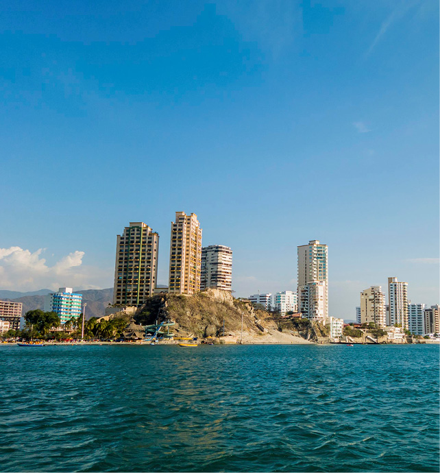 city skyline with the ocean in front of it and blue skies