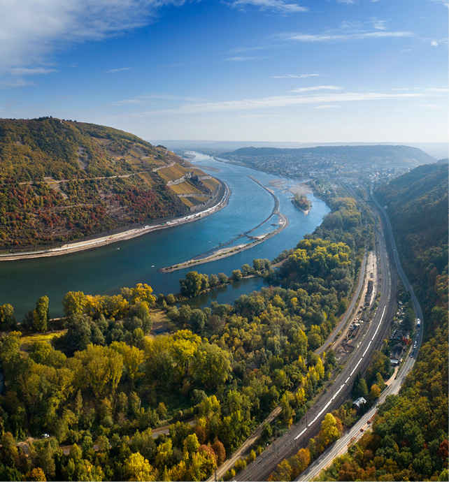 Bend of the Rhine river with lush green landscapes either side, showcasing the vineyards of the wine region 