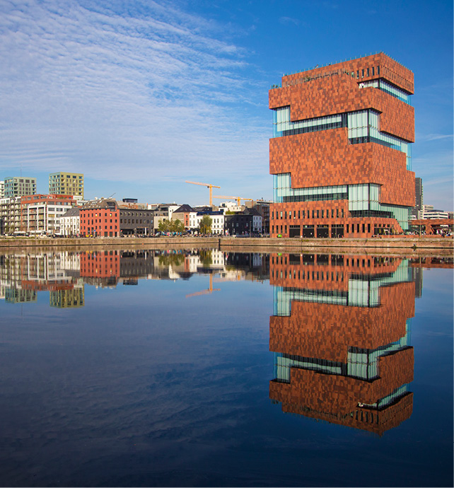 red brick buildings next to still water with clear reflections