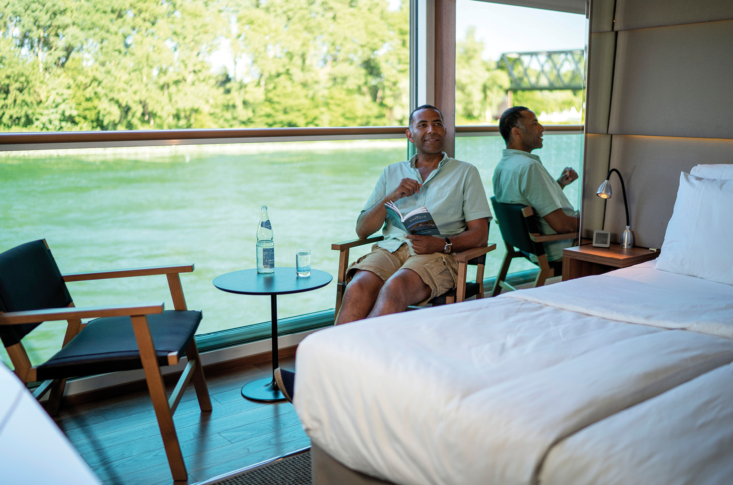 A man sitting by the balcony in a Balcony Suite on a river cruise