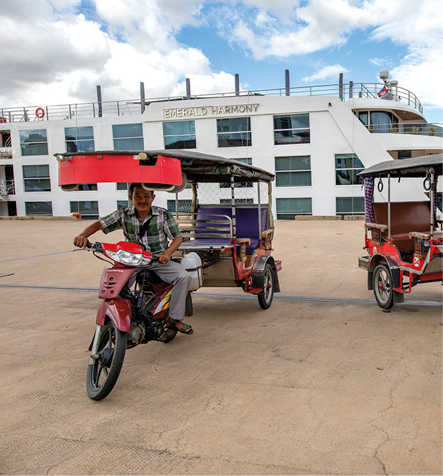 Tuk-tuk rides parked outside a Southeast Asia river ship