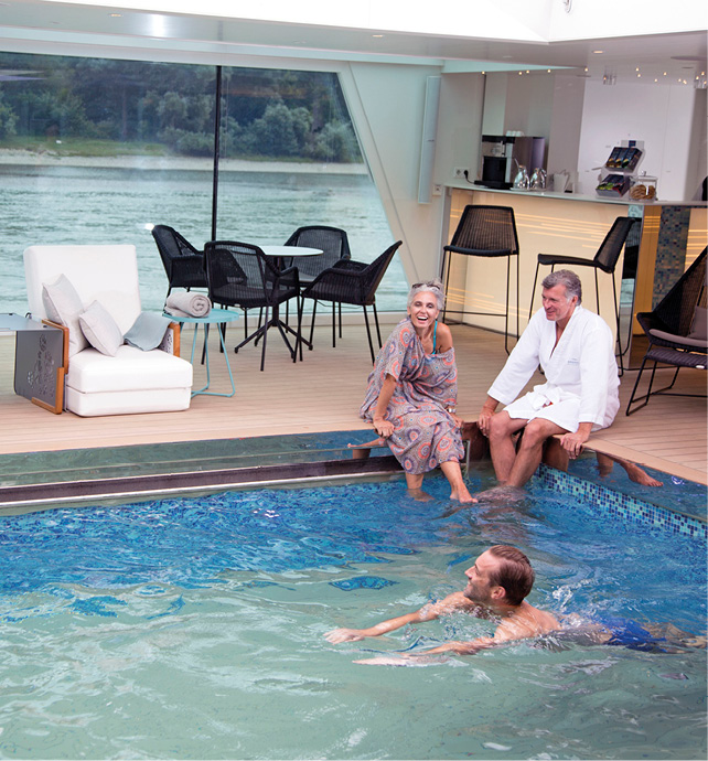 Two couples enjoying the pool, with a man swimming and a couple dangling their feet in the cooling waters